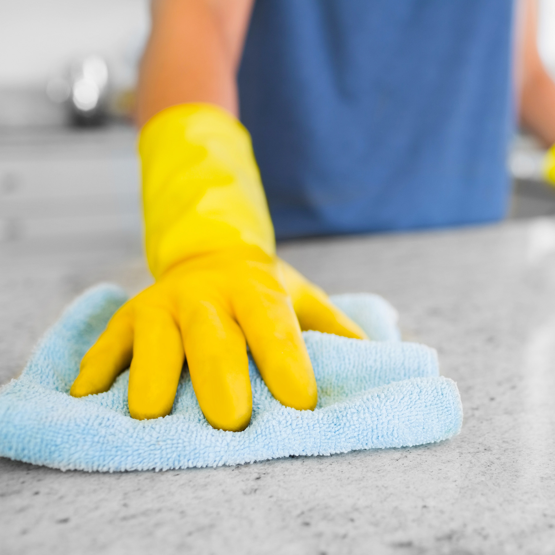 gloved hand cleaning kitchen counter with rag
