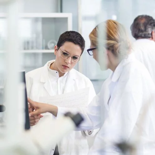 Two women in lab coats reviewing data